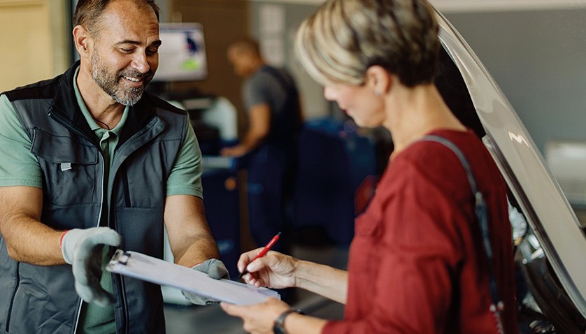 Technician going through paperwork on a clipboard with a customer